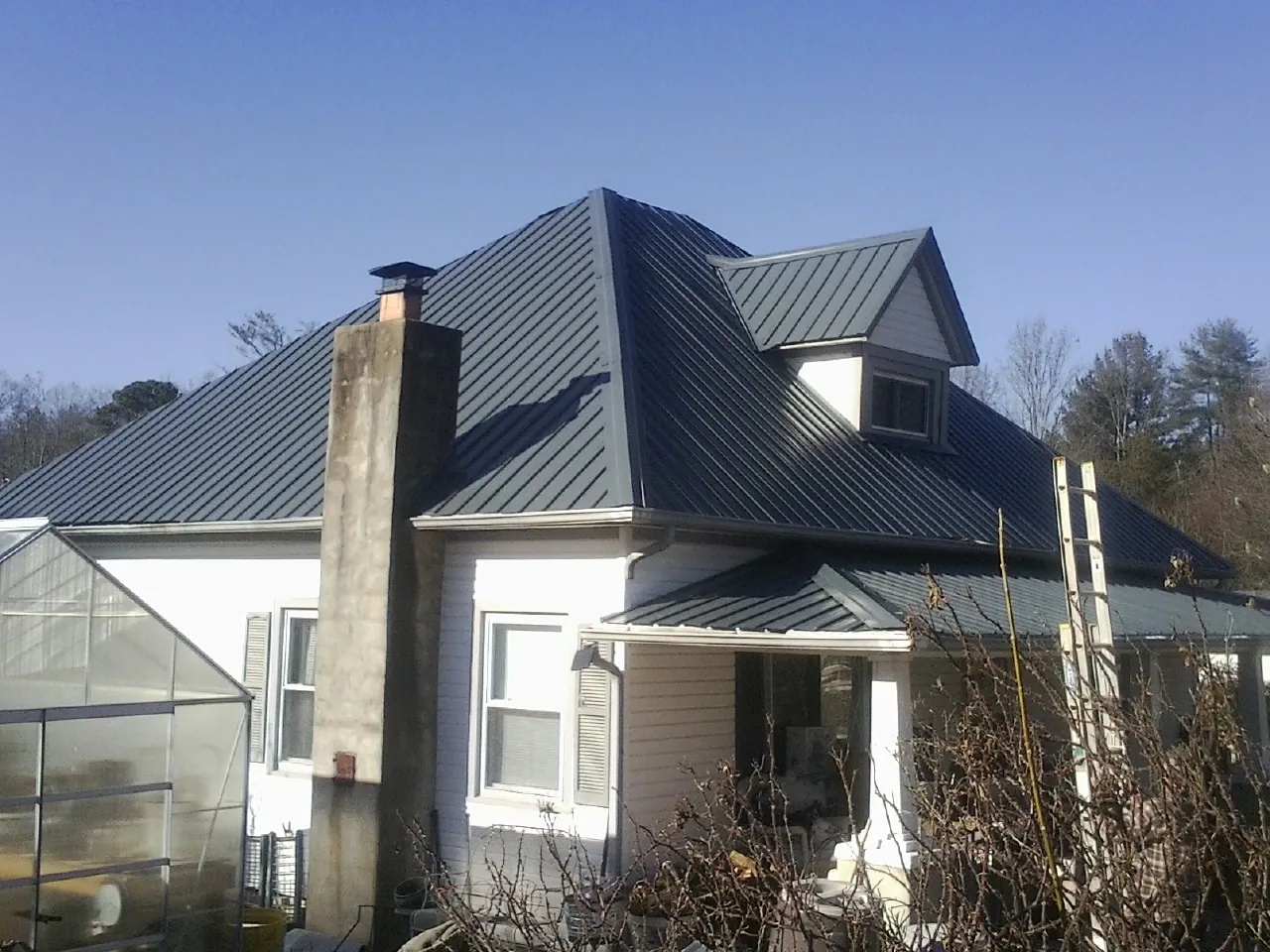 Dark blue standing seam metal roof on a white farmhouse with dormer — Slate & Tile Roof Repair by Roofing Brothers in Bethlehem