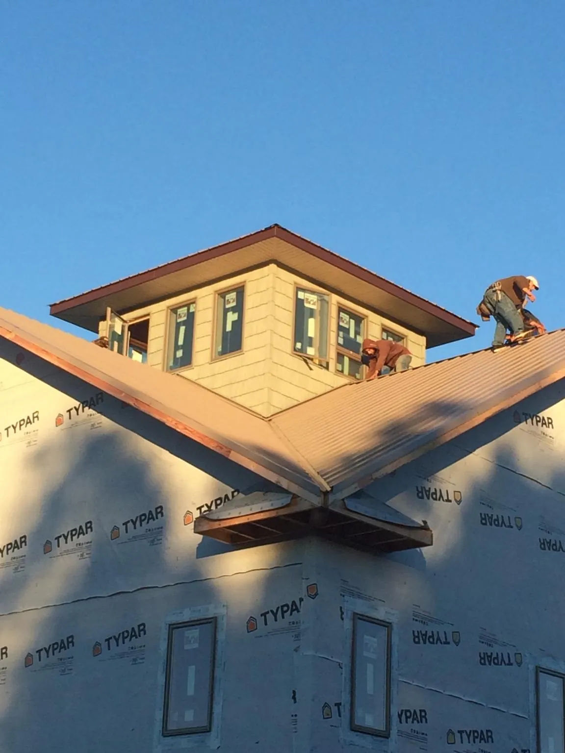 Roofers working around a rooftop cupola on a new metal roof at sunset — Roof Waterproofing in Bethlehem by Roofing Brothers